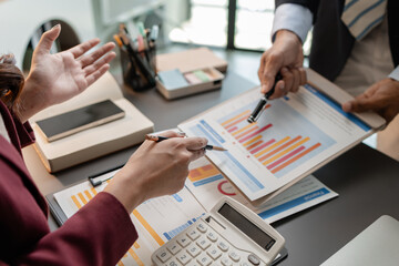 Business professionals meeting at a modern office table, reviewing charts and budget reports while discussing key financial insights and strategic plans for upcoming business decisions.