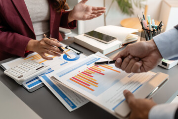 Business professionals meeting at a modern office table, reviewing charts and budget reports while discussing key financial insights and strategic plans for upcoming business decisions.