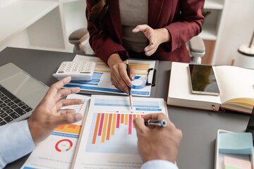 Business professionals meeting at a modern office table, reviewing charts and budget reports while discussing key financial insights and strategic plans for upcoming business decisions.