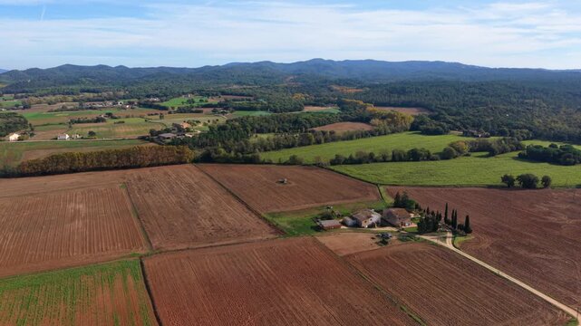 Aerial view flying over farmhouse and plowed fields in rural spain