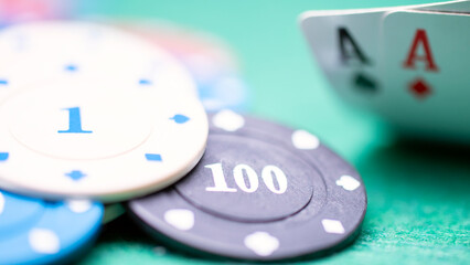 A pile of poker chips with the numbers 1, 100, and A on them. The chips are on a green table