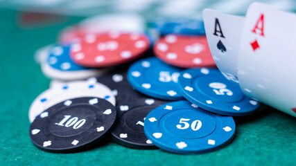A pile of poker chips with numbers 50 and 100 on them. The chips are scattered on a green table