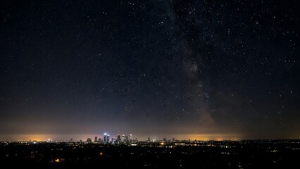 City skyline at night with stars and Milky Way visible in the dark sky