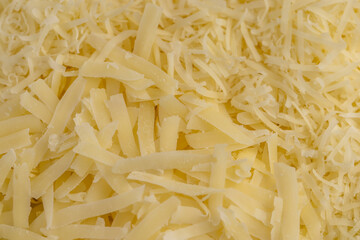 finely grated yellow cheese on a grater for pizza or pasta, yellow grated cheese with pieces for cooking various foods