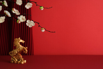 Golden horse statue in front of a red pleated curtain and white plum blossoms branch. Happy Chinese...