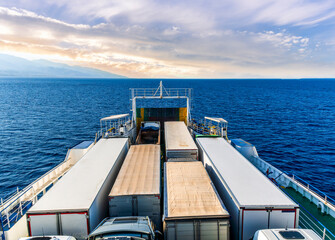 sea cargo boat ferry lines transpotring cargo trade freigh goods to port through ocean. Naval commercial ship carring trucks with carriage in blue sea.  Seascape with shipping cargo ferry.