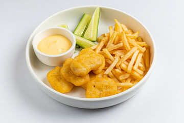 Delicious chicken nuggets with golden fries alongside cool cucumber slices and creamy dip