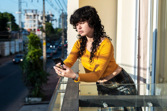 Modern latina in connected pause with smartphone near the busy city street