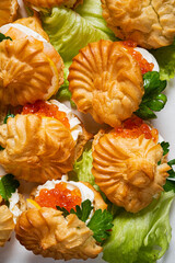 Flaky pastries filled with creamy goodness and bright salmon roe sit atop crisp lettuce leaves