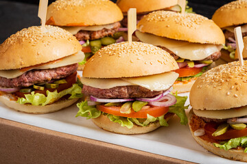 A lively setting showcases freshly made burgers stacked high with colorful toppings, ready to enjoy