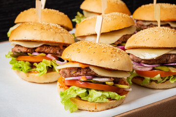 Six delicious burgers are artfully arranged with vibrant toppings, inviting a tasty experience