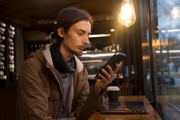  remote workers. Working from Anywhere.  a young man is working on a laptop in a cafe and drinking coffee
