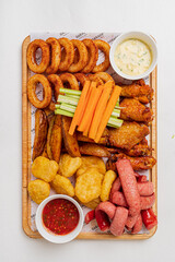 A variety of crispy snacks like chicken wings, onion rings, and veggies are beautifully arranged