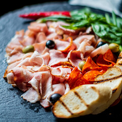 A vibrant spread showcases various cured meats, olives, and herbs, perfect for sharing