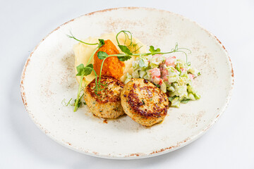 Savory seafood cakes accompanied by colorful salad and smooth mashed potatoes create a feast