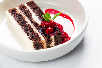 Chocolate cake layers with creamy filling, topped with cherries and mint, ready to enjoy!