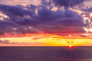 Dramatic seascape of sunset or sunrise sky with clouds during morning or evening. Dramatic sunset over the sea with orange clouds and sun above ocean water