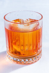A vibrant cocktail with ice sits in a beautifully designed glass, giving a refreshing vibe
