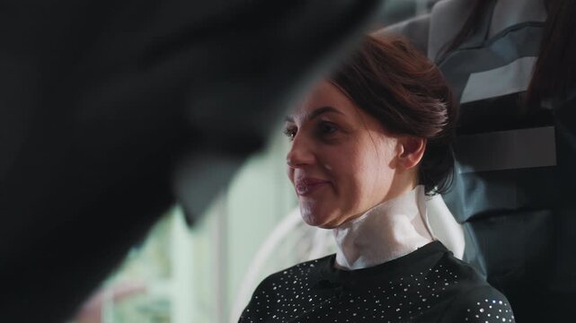 client eagerly anticipates new hairstyle today, relaxed woman waits as stylist prepares to give new look, casually seated woman enjoys anticipation before her fresh hairstyle transformation