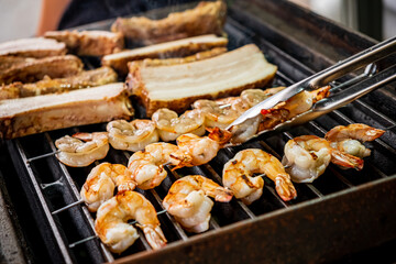 Friends gather at a summer barbecue, grilling shrimp and succulent pork on an outdoor grill