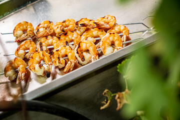Juicy shrimp skewers are grilling, releasing delicious aromas on a warm sunny day outdoors