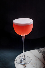 A beautifully crafted cocktail in a delicate glass showcases a vibrant pink hue, inviting to enjoy