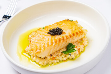 Delicious salmon fillet elegantly plated, showcasing its golden crust and caviar garnish