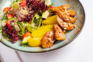 A vibrant salad of crisp greens, juicy strawberries, and tender chicken with pine nuts