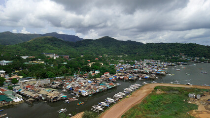 Wide angle panoramic view of Coron town harbor and green islands scattered in blue sea under cloudy sky in Philippines