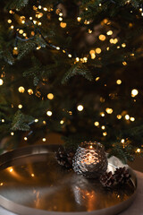 Christmas holiday aesthetic festive background in dark tone, blurred Christmas tree with golden garland light bokeh, bronze tray with candle light, soft selective focus, copy space