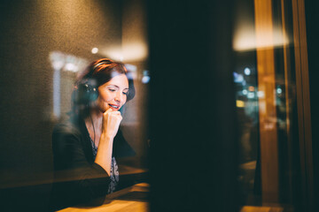 Privacy booth office interior with woman using headset for communication in modern workspace, warm lighting creates focused and comfortable atmosphere for professional work and concentration