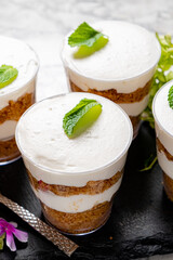 Creamy layers of dessert in transparent cups are topped with mint and inviting flavors