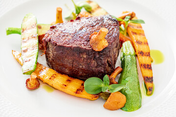 A juicy steak on a plate, surrounded by grilled veggies, showcases culinary artistry