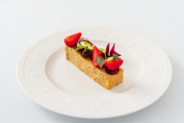 A delectable slice of dessert beautifully presented with strawberries, chocolate, and herbs