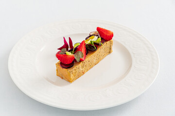 A tempting dessert slice with smooth texture, fresh strawberries, and colorful greens entices all