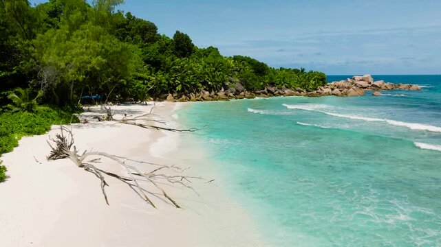 Sandy beach surrounded by tropical vegetation and large boulders. Anse Cocos beach, Seychelles.