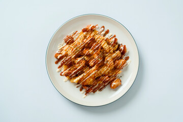Fried fries topped with mayonnaise, mozzarella, and cheese, served on a white plate. flat lay food concept