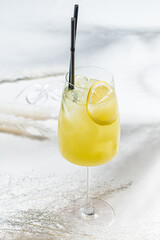 A bright yellow cocktail with a lemon slice sits on ice, inviting enjoyment