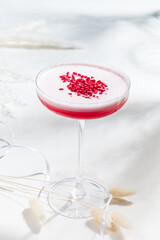 A creamy cocktail with white layers and vibrant raspberry pieces invites delight
