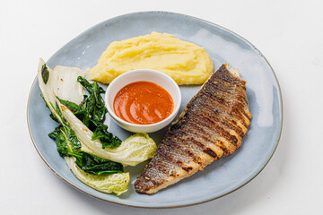 Succulent grilled fish accompanied by smooth mashed potatoes and vibrant stir-fried greens