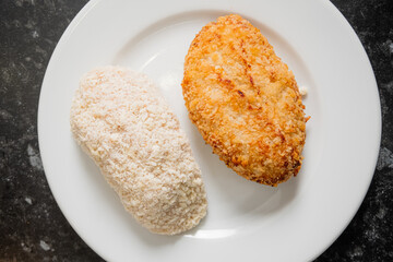 Two chicken cutlets await frying, one coated with flour and the other with golden breadcrumbs