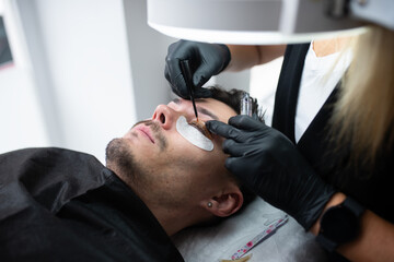 A young man in a beauty salon taking care of eyelashes