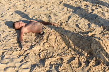 Portrait of a boy buried in sand