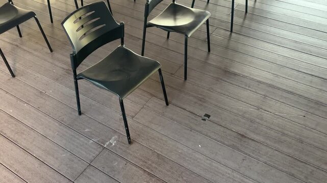 Cinematic shot captures rows of black chairs on a wooden floor, camera moving upward from below to the center of the frame.Scene conveys a sense of organization, perfect for event planning.