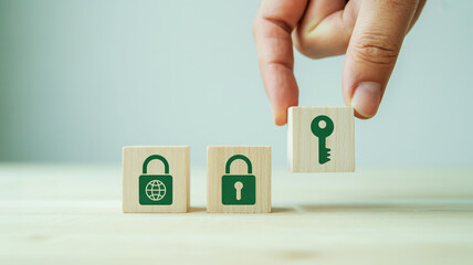 Hand placing wooden cube with key symbol next to cubes with lock symbols on table security access