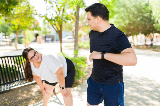 Fit diverse couple working out together outdoors, taking a break during their fitness training in a park - Powered by Adobe