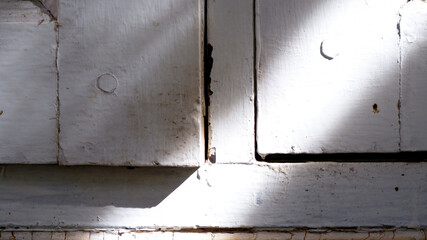 Close-up old wooden door frame with diagonal sunlight on its surface. Abstract rustic texture background of white wooden. Dirty, aged, shade, vintage, corner, natural light concept for background.