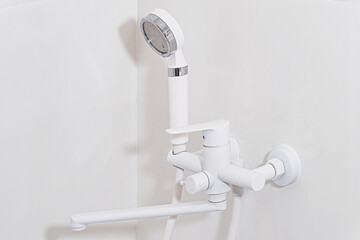 modern white shower mixer tap with handheld head in minimalist bathroom