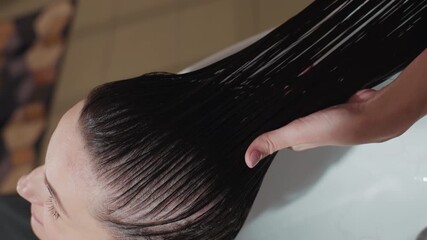 client experiences soothing hairstyling routine, stylist expertly manages moist hair with delicate technique, client with visible skin calmly receives meticulous and gentle hair detangling