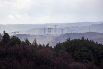 High-voltage power lines crossing misty forested hills.